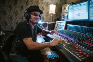 Musiker mit Kopfhörern bedient ein großes Mischpult im Tonstudio