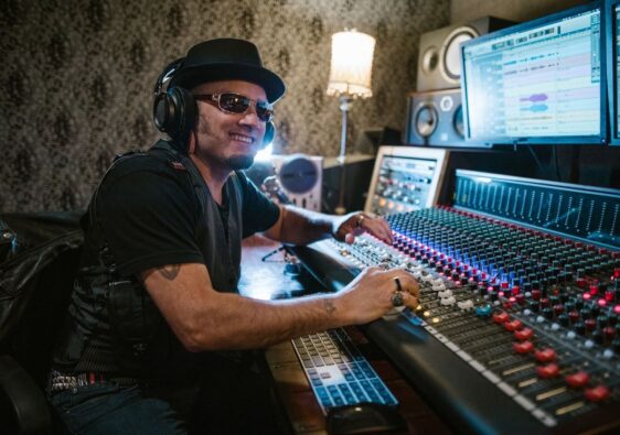Musiker mit Kopfhörern bedient ein großes Mischpult im Tonstudio