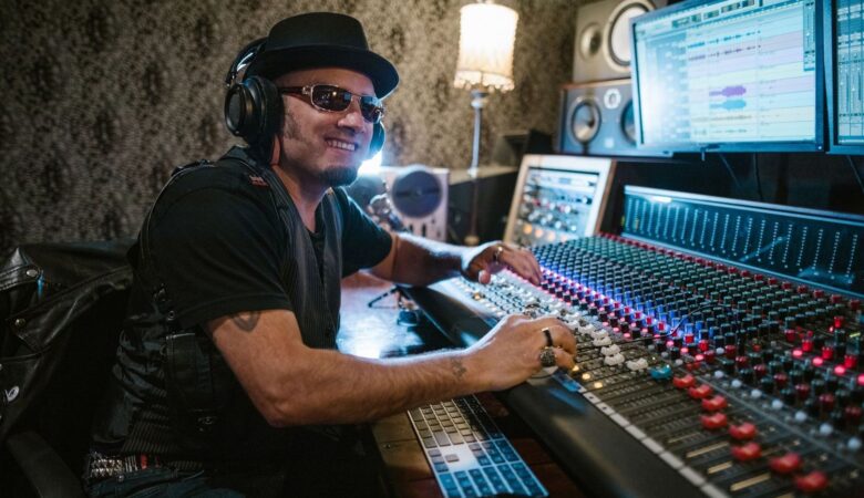 Musiker mit Kopfhörern bedient ein großes Mischpult im Tonstudio