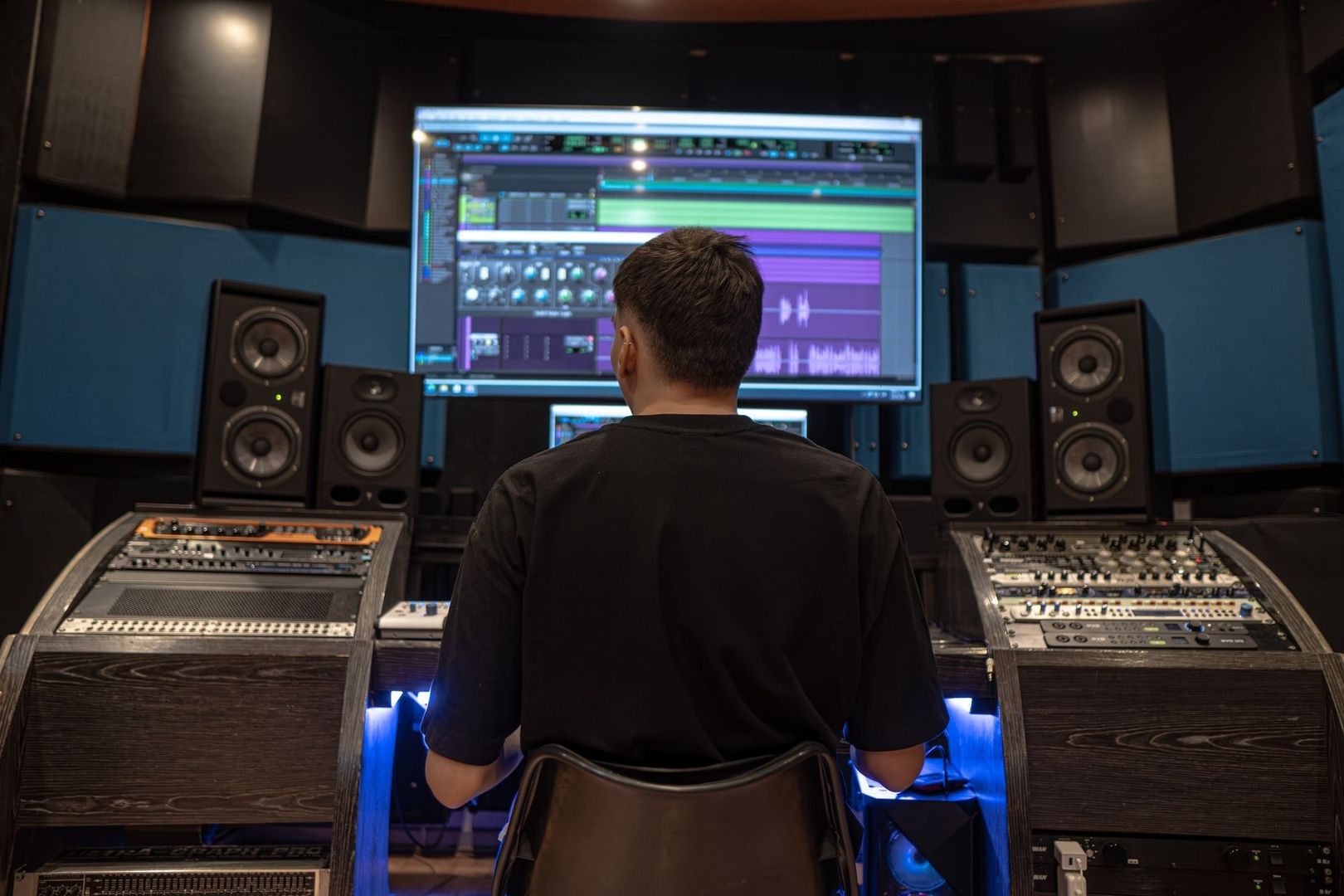 Person arbeitet an Mischpult und DAW in einem Tonstudio